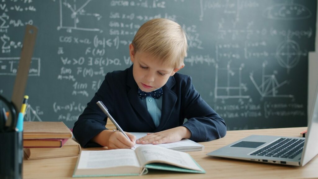 Young boy in a suit writing at a desk