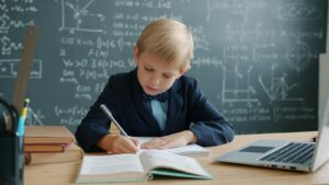Young boy in a suit writing at a desk